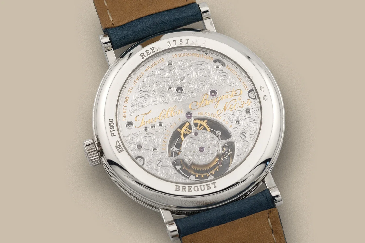 Close-up of a luxury Breguet wristwatch with a detailed skeleton dial and visible mechanical movement, leather strap, and engraved branding.