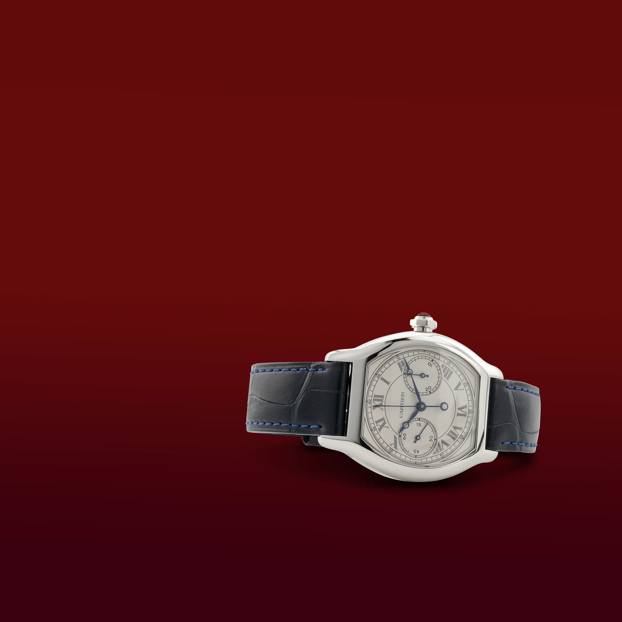 A close-up view of a silver wristwatch with a black strap against a red background.