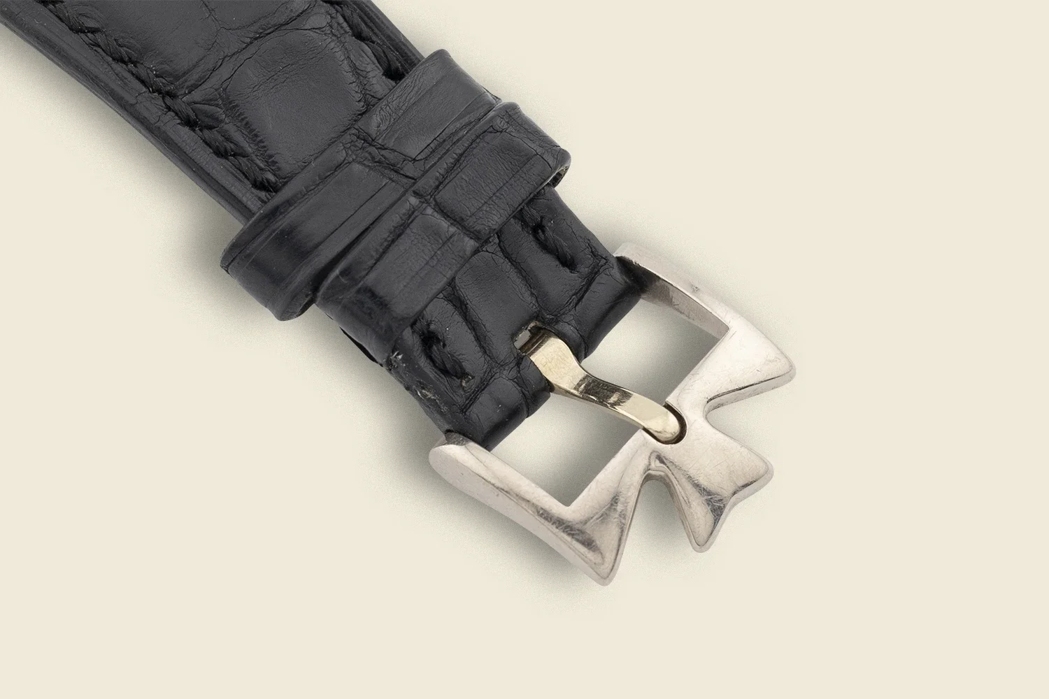 Close-up of a black leather watch strap with a silver buckle.