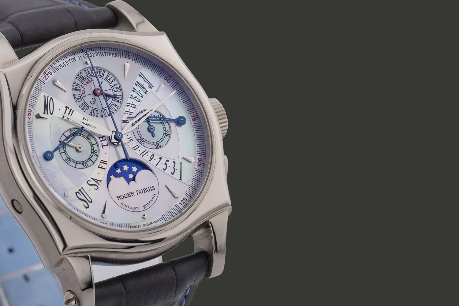 Close-up of a luxury Roger Dubuis wristwatch with multiple dials, moon phase display, and a leather strap.