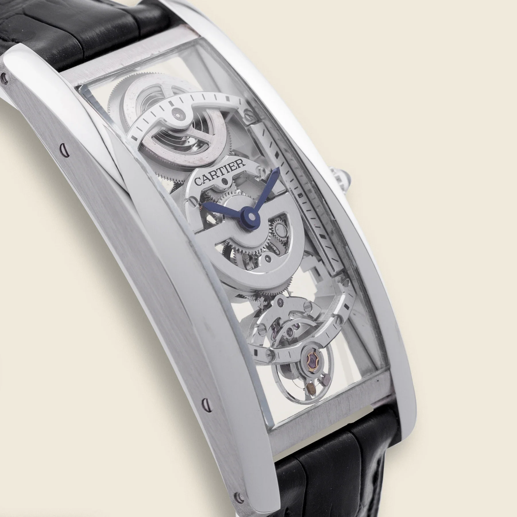A close-up view of a luxury skeleton watch with a transparent case revealing intricate internal gears and mechanisms, mounted on a black strap.