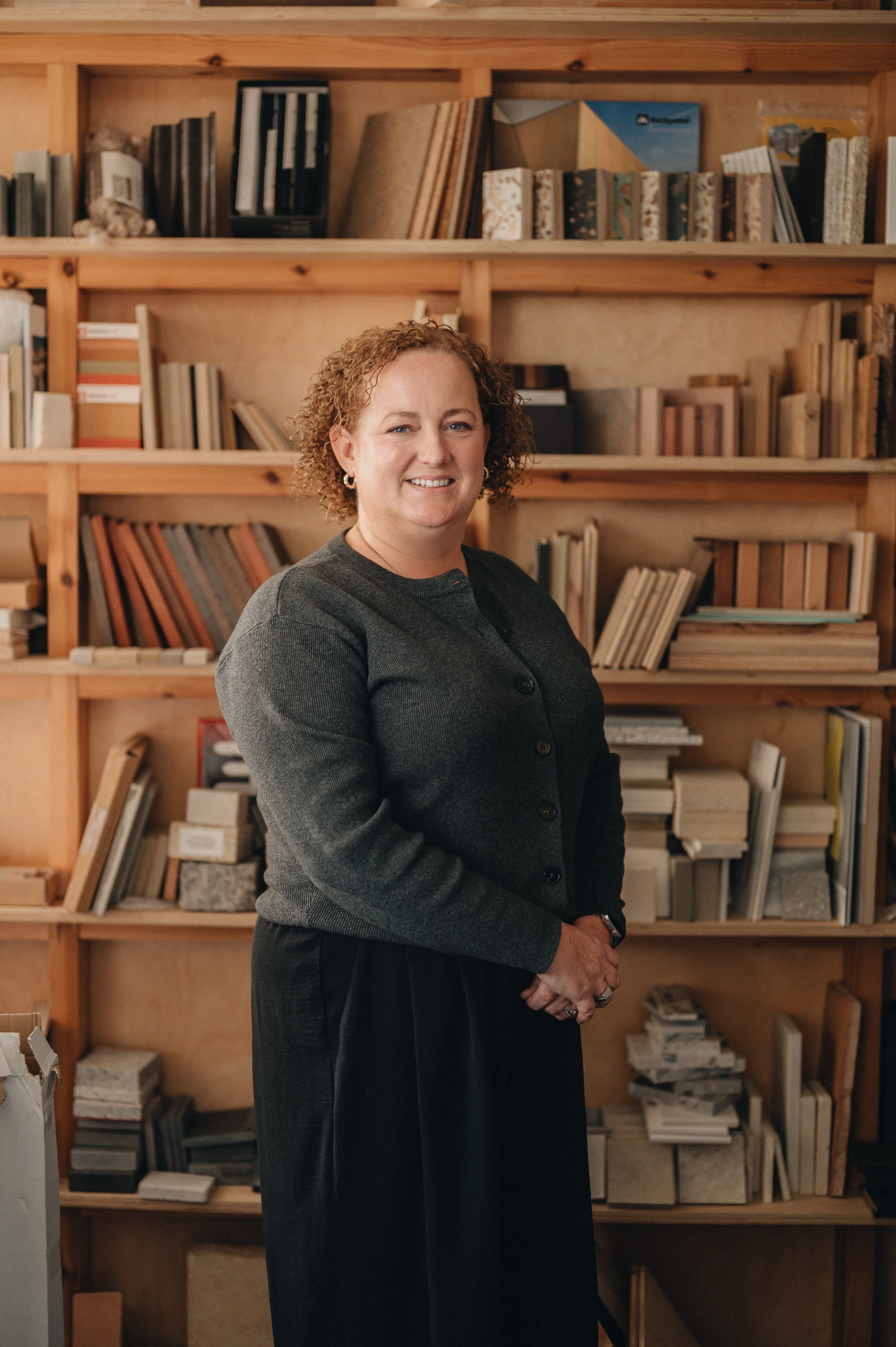 Smiling woman standing in front of wooden bookshelves filled with books