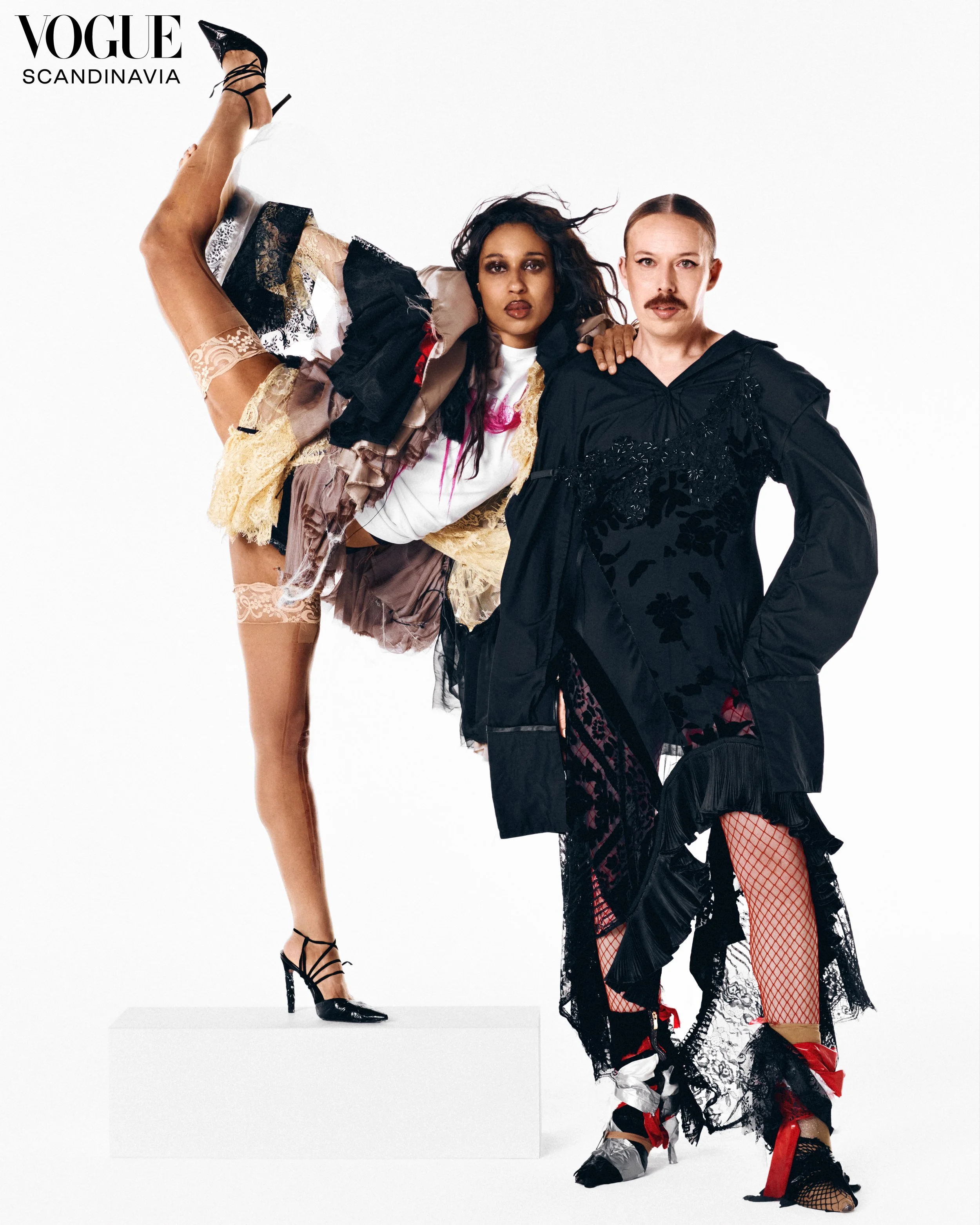 fashion magazine cover with two models dressed in avant-garde black and lace clothing, posing against a plain white background, with the Vogue logo and 'Scandinavia' written at the top.