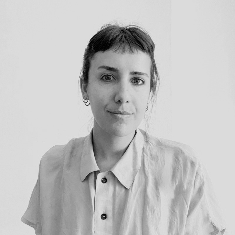 Black and white photo of a woman with short hair, wearing a button-up shirt, looking at the camera with a slight smile.