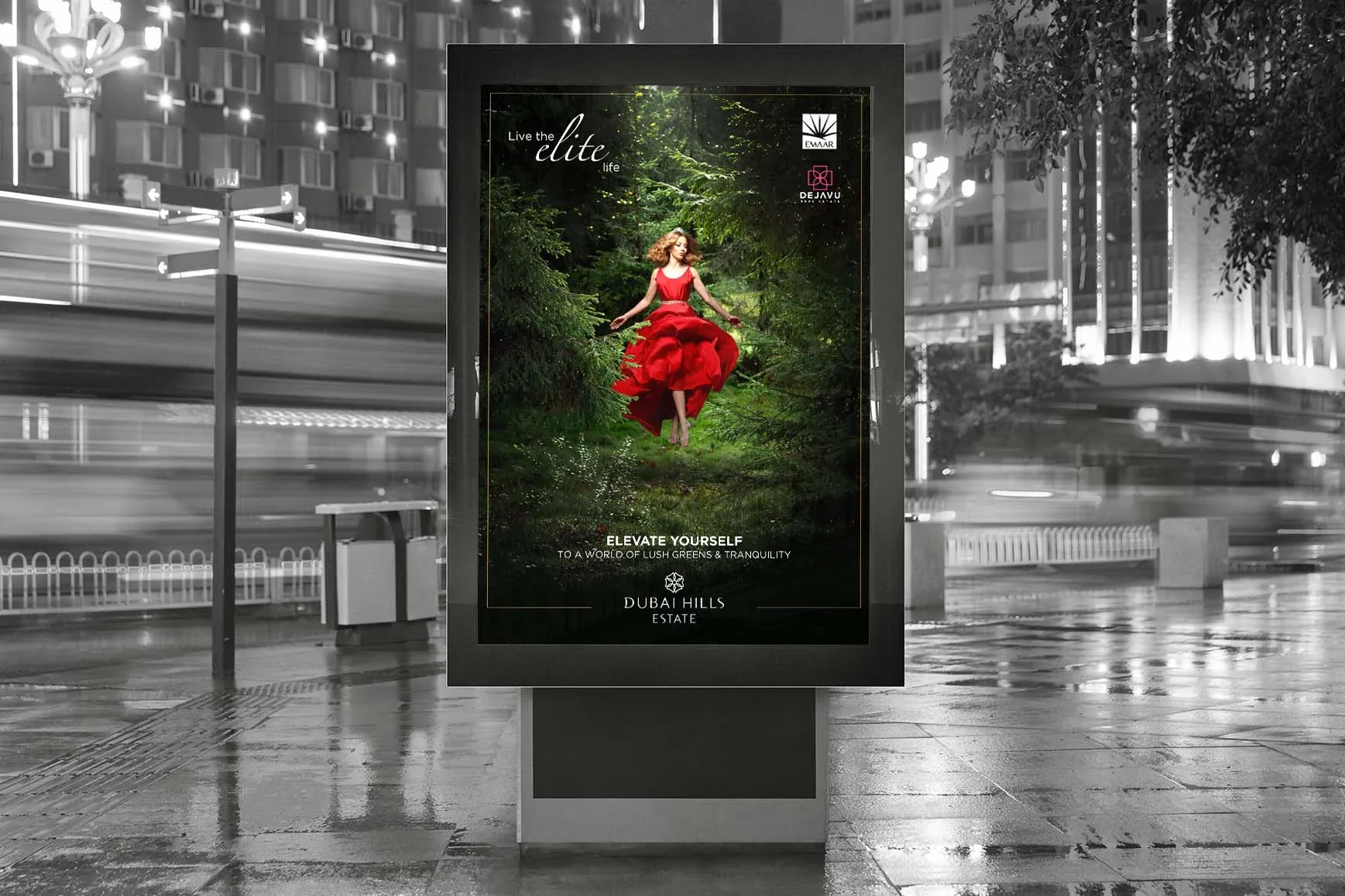 Digital billboard advertisement for Dubai Hills Estate featuring a woman in a red dress jumping in a lush green forest setting with the text "Live the elite life" and "Elevate Yourself to a world of lush greens & tranquility."