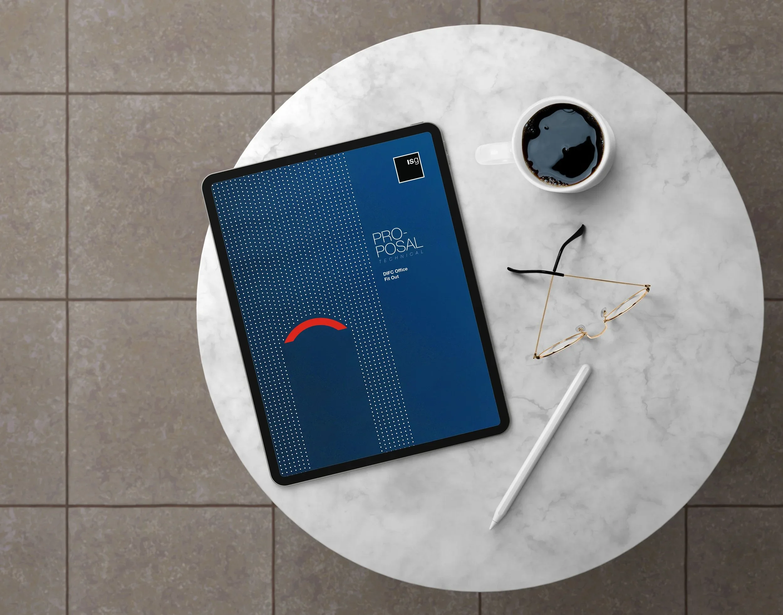 Top-down view of a round white table with a tablet displaying a digital graphic, a cup of black coffee, glasses, and a white stylus.