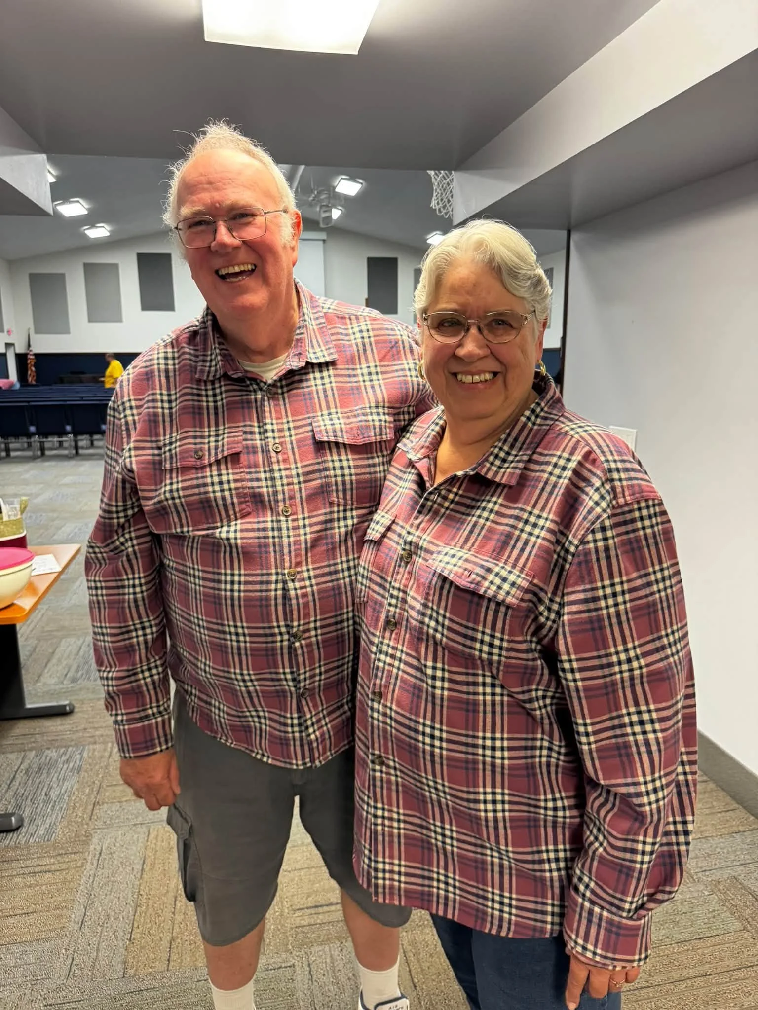 Smiling older couple wearing matching plaid shirts in a community gymnasium