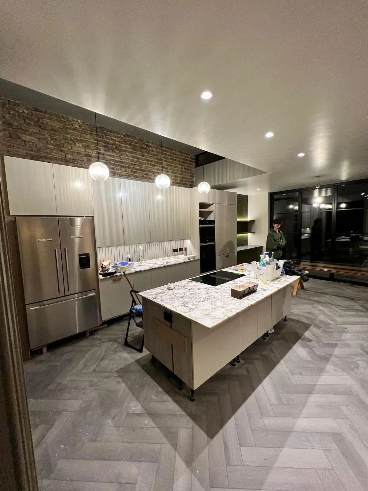 Modern kitchen with marble island, stainless steel appliances, and hanging globe lights