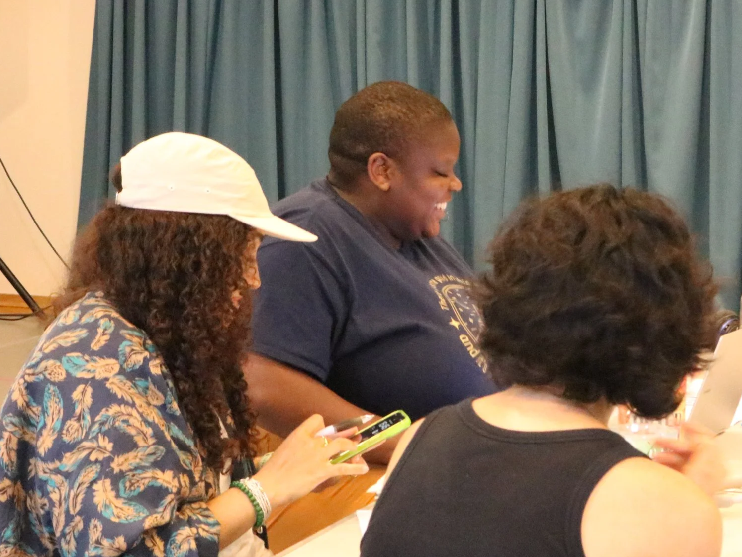 Group of three people sitting at a table with dark blue curtains in the background.