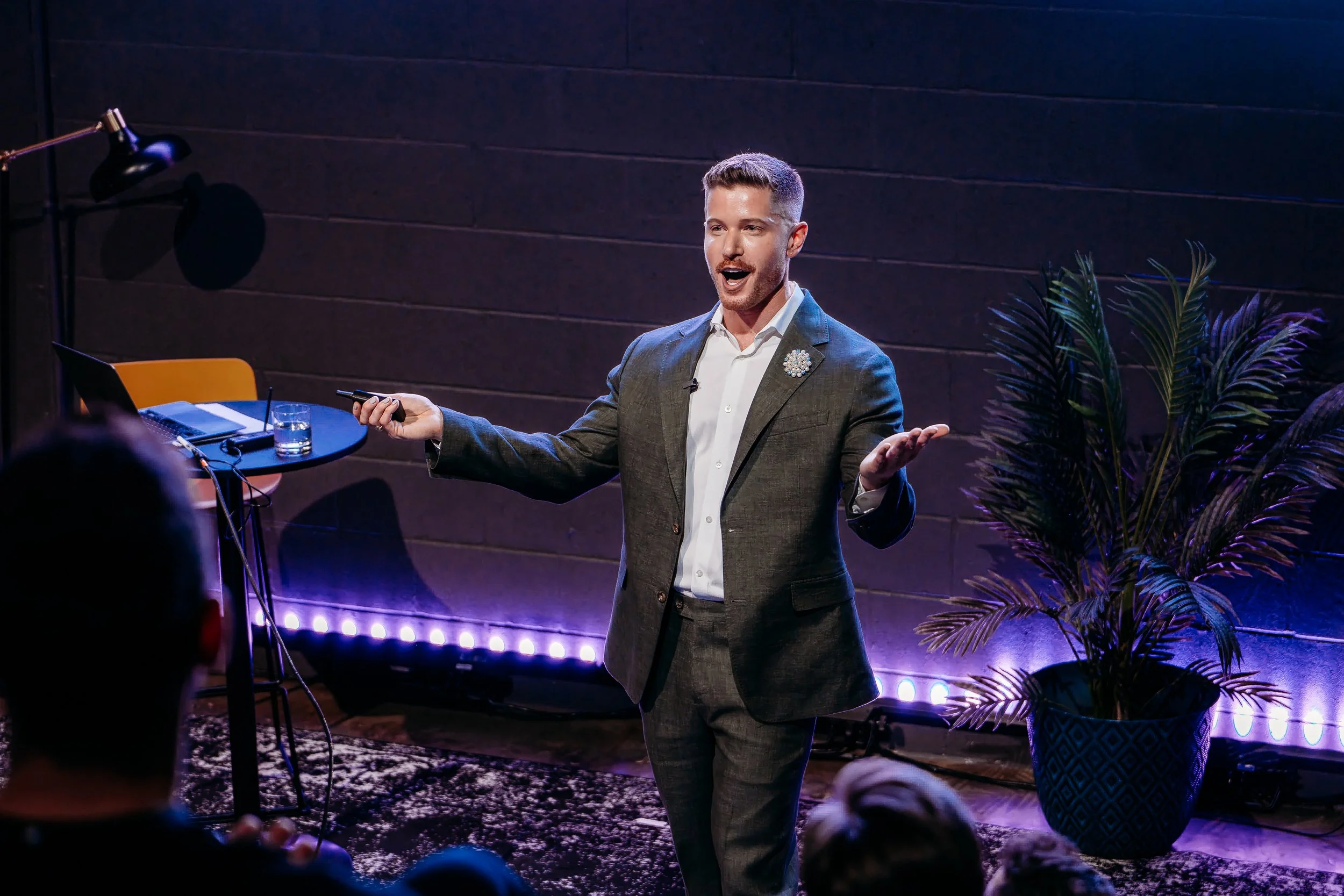 Blake Mitchell speaking on a colorfully lit stage before an audience