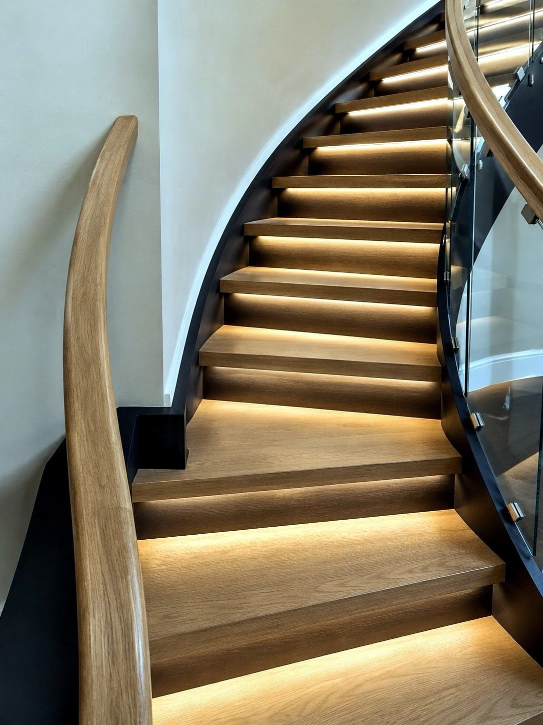 Curved stair with lighted treads and glass railing