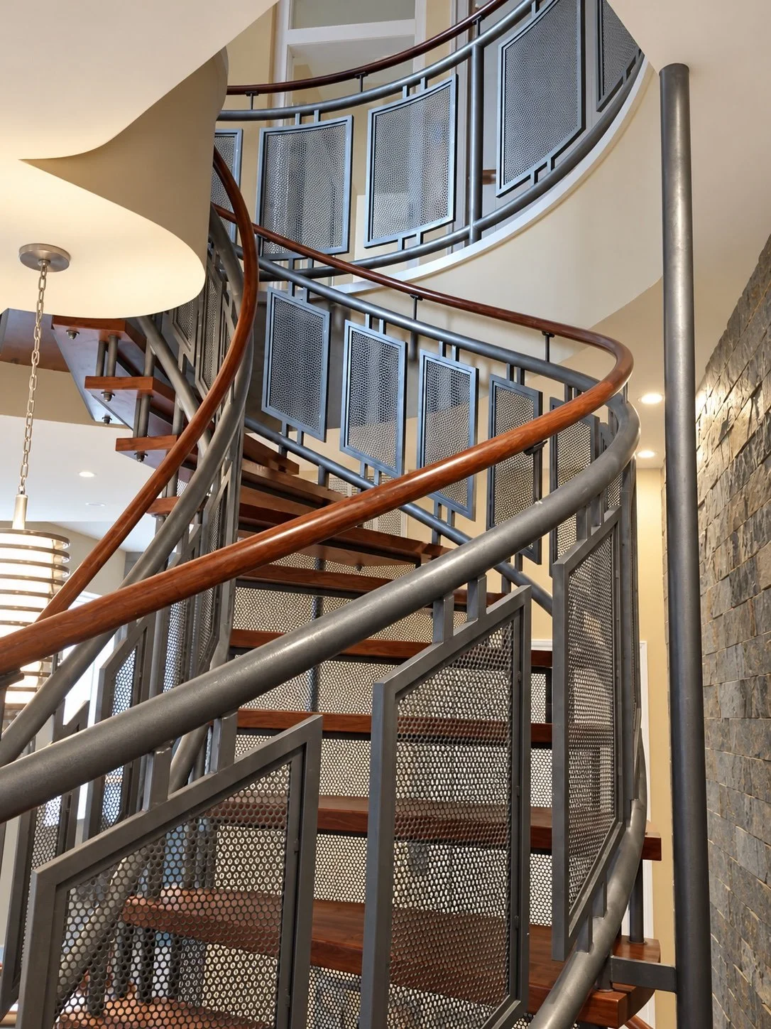 Curved mesh stair from the side, with stone wall