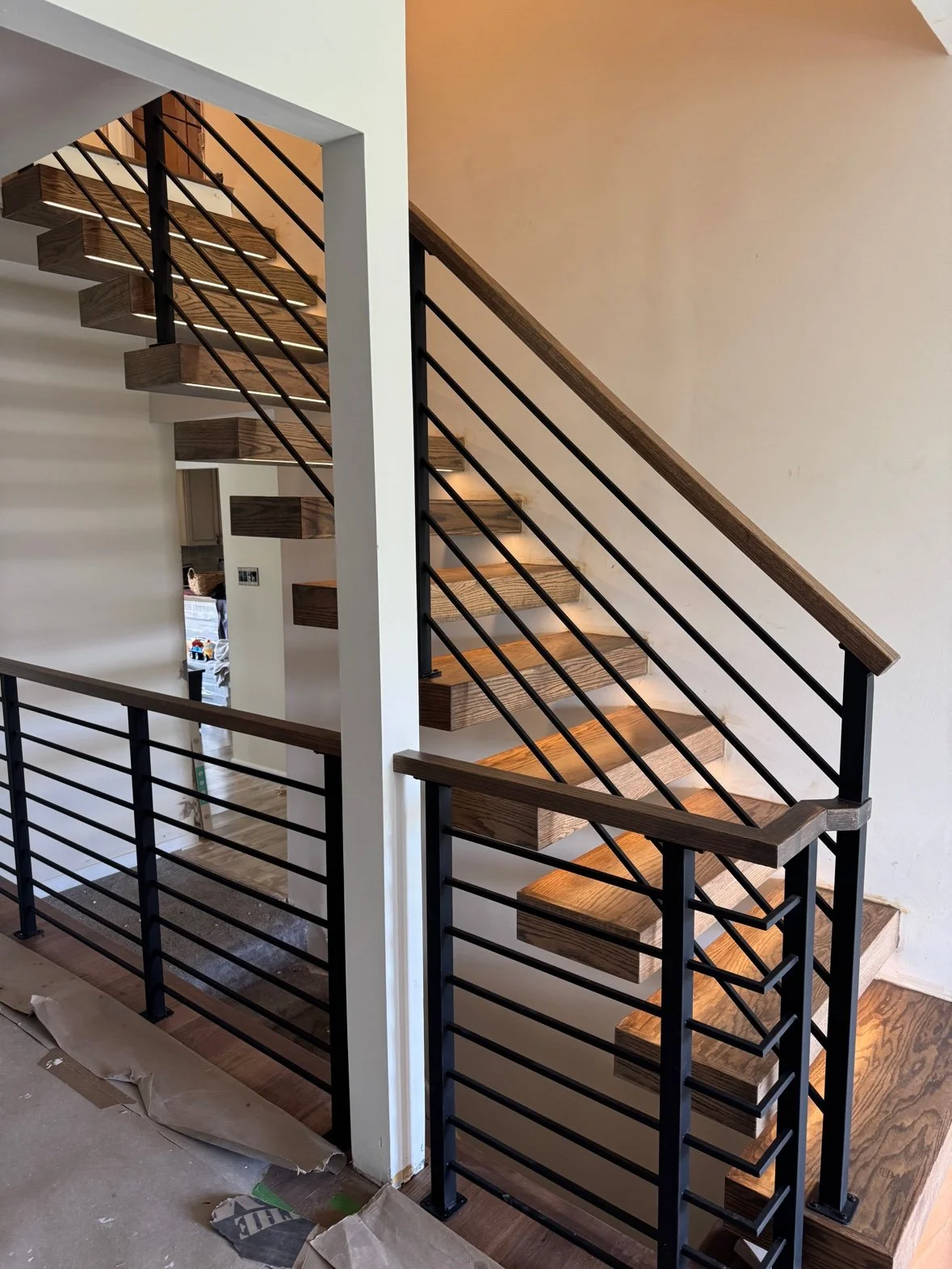 Flight with horizontal-bar railing and wood handrail, seen from the landing