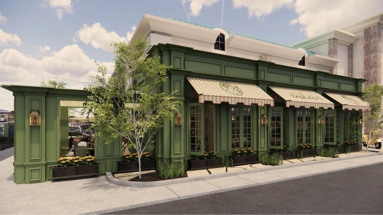 Green storefront with striped awnings, outdoor lighting fixtures, and potted plants, in a sunny area with a sidewalk and trees.