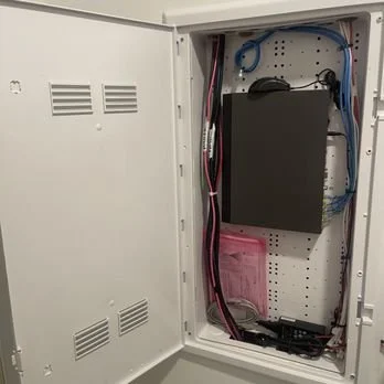 Open electrical enclosure with wiring, circuit components, and a black equipment module