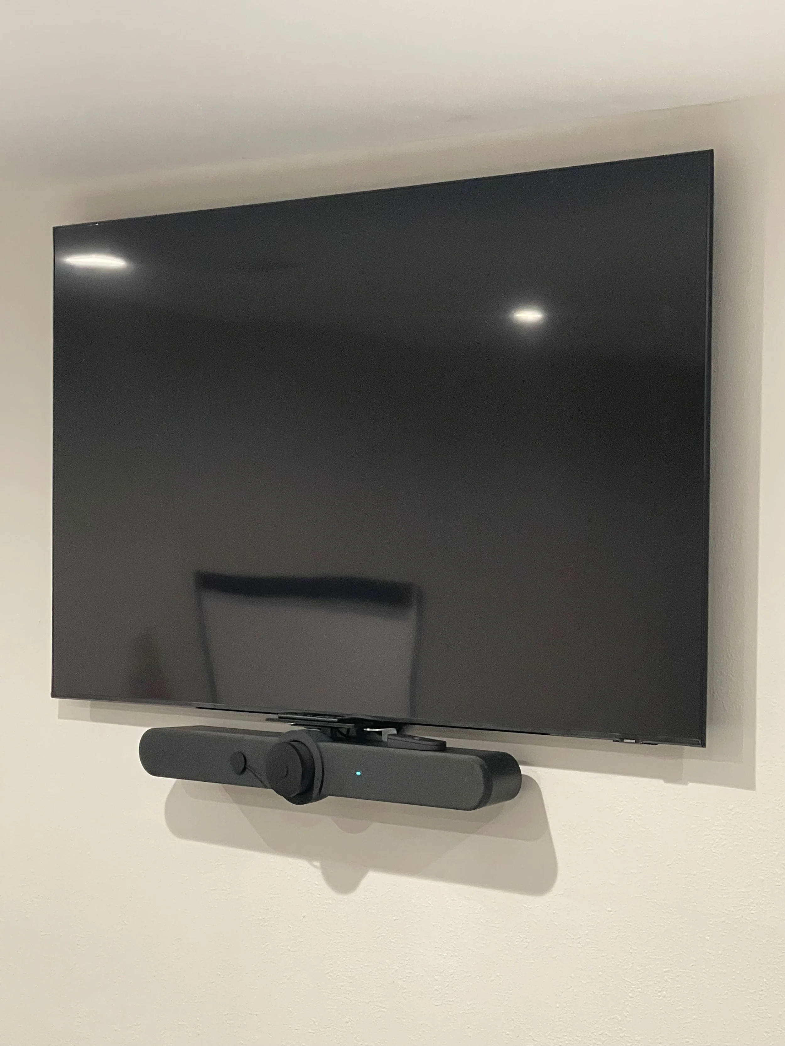 Wall-mounted flat-screen TV with a black soundbar beneath it