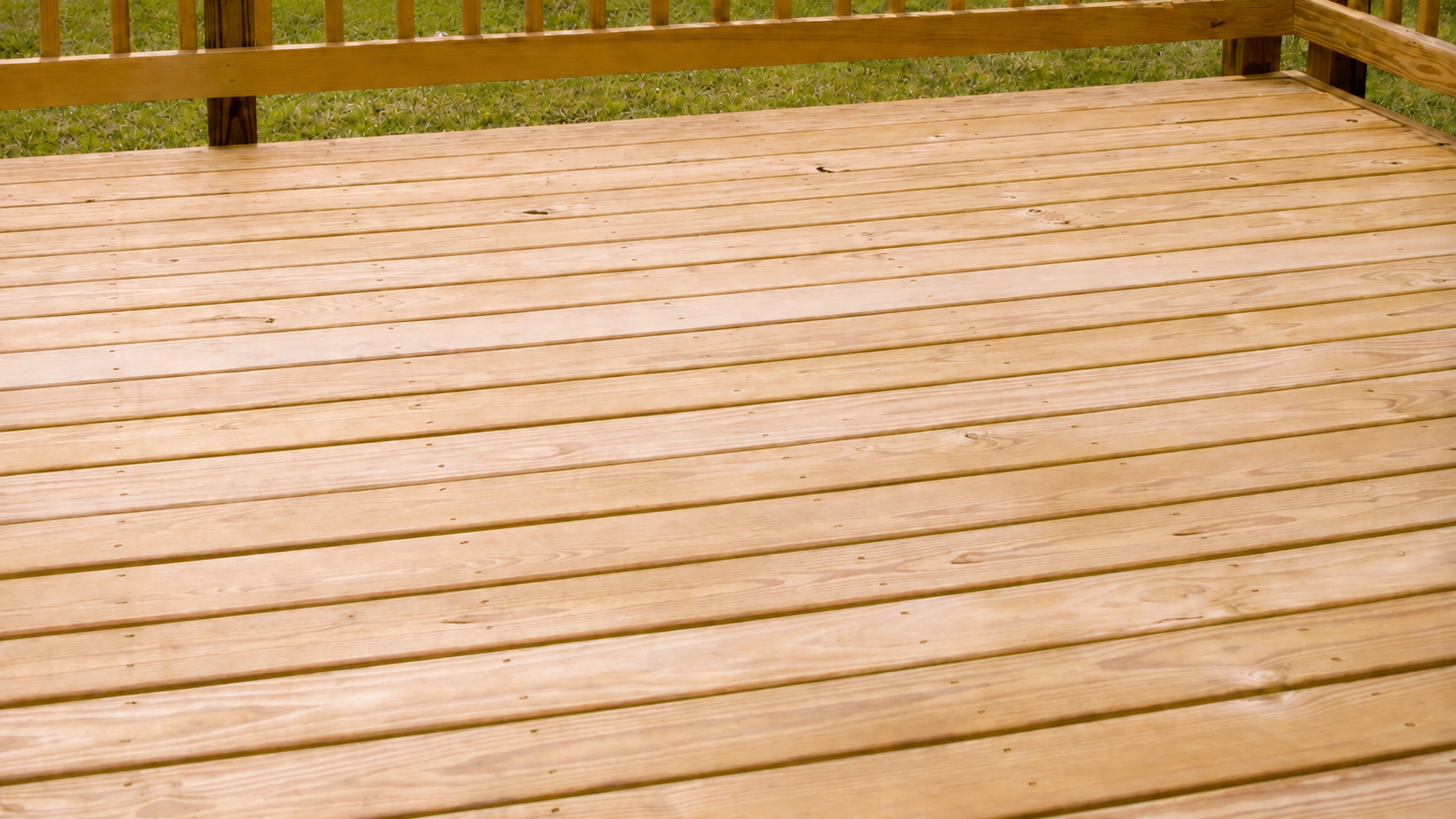 Newly constructed wooden deck with railings and grassy yard beyond