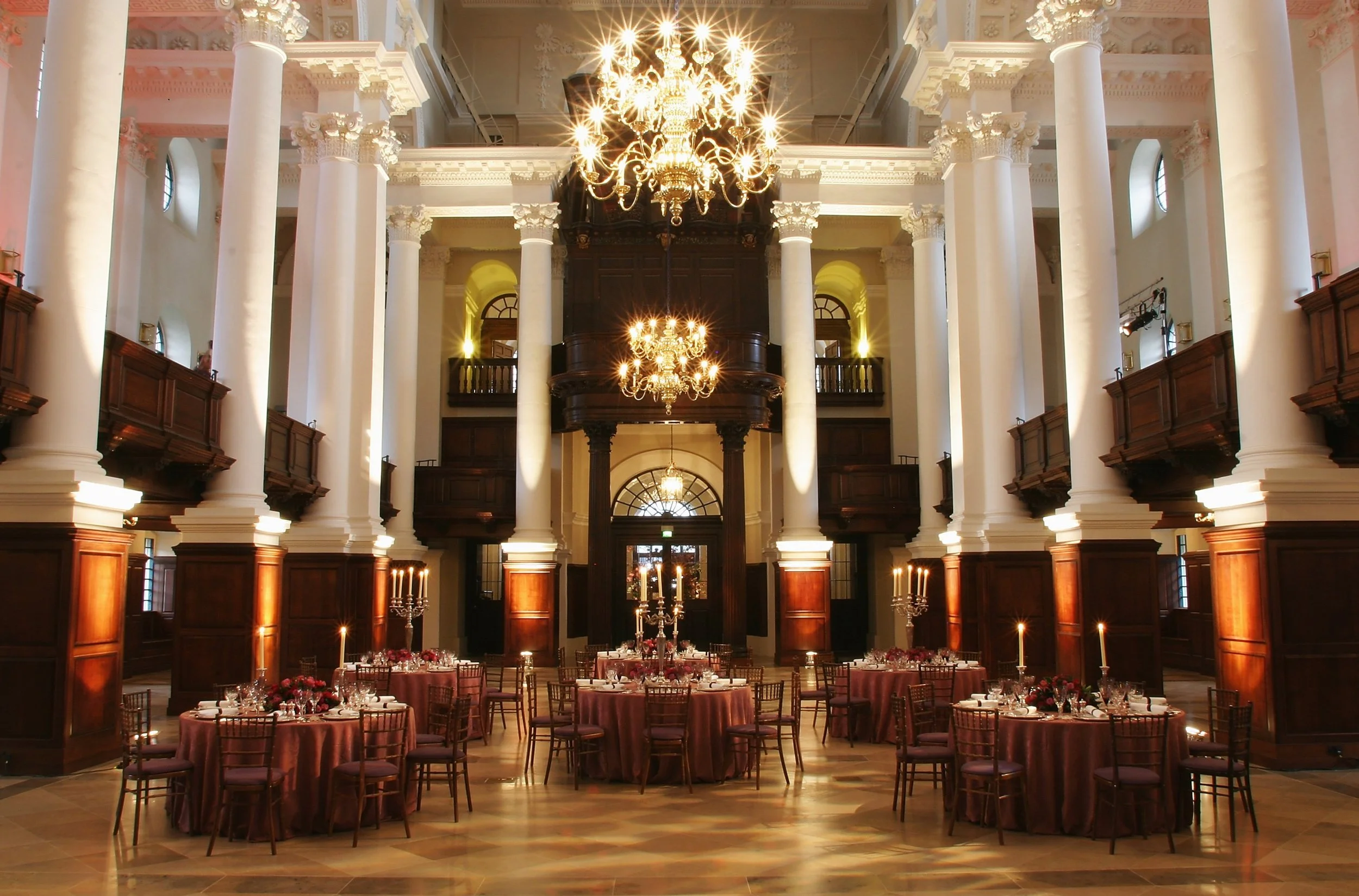 The Nave at Christ Church Spitalfields set for a gala dinner with round tables beneath illuminated chandeliers