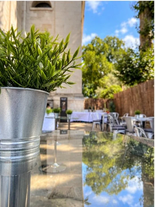 Greenery, glass tables and seating in the sunlit Courtyard at Christ Church Spitalfields.