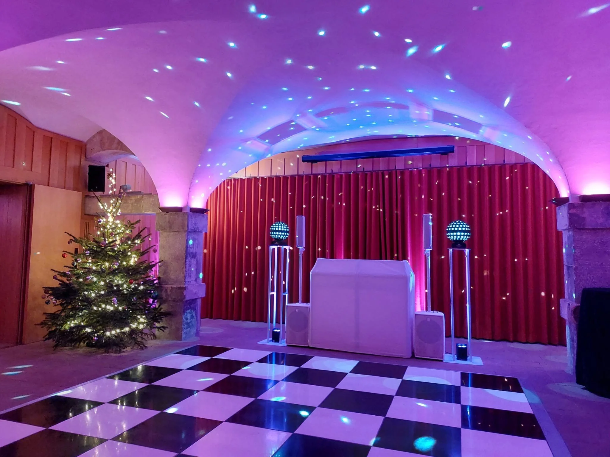 Christmas tree and DJ booth in the Crypt, lit in pink and purple for a festive party