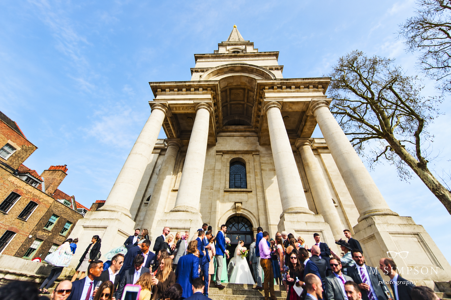 Bride and wedding guests gathered on the steps beneath Christ Church Spitalfields’ portico.