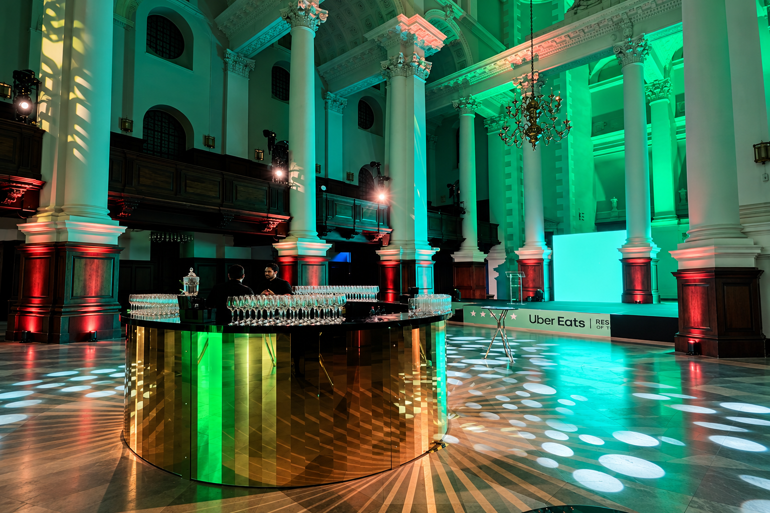 Circular gold bar in the Nave at Christ Church Spitalfields, beneath chandeliers and green event lighting