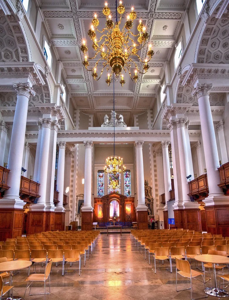 The Nave at Christ Church Spitalfields arranged with rows of chairs beneath its columns and chandeliers