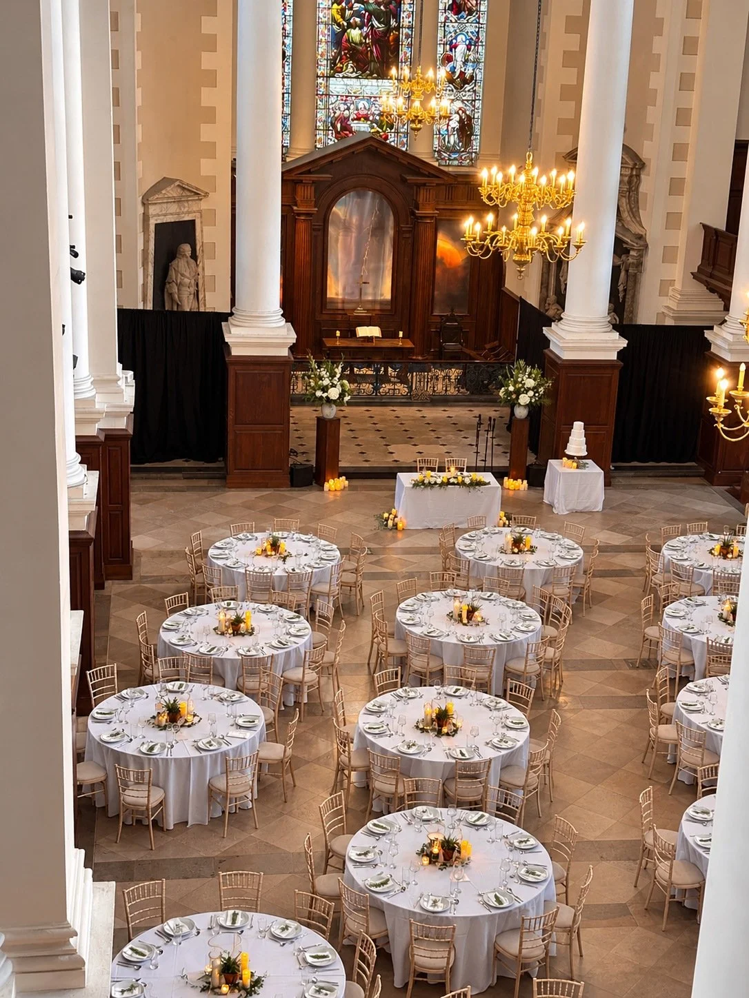 Round wedding tables beneath the chandeliers in the Nave.