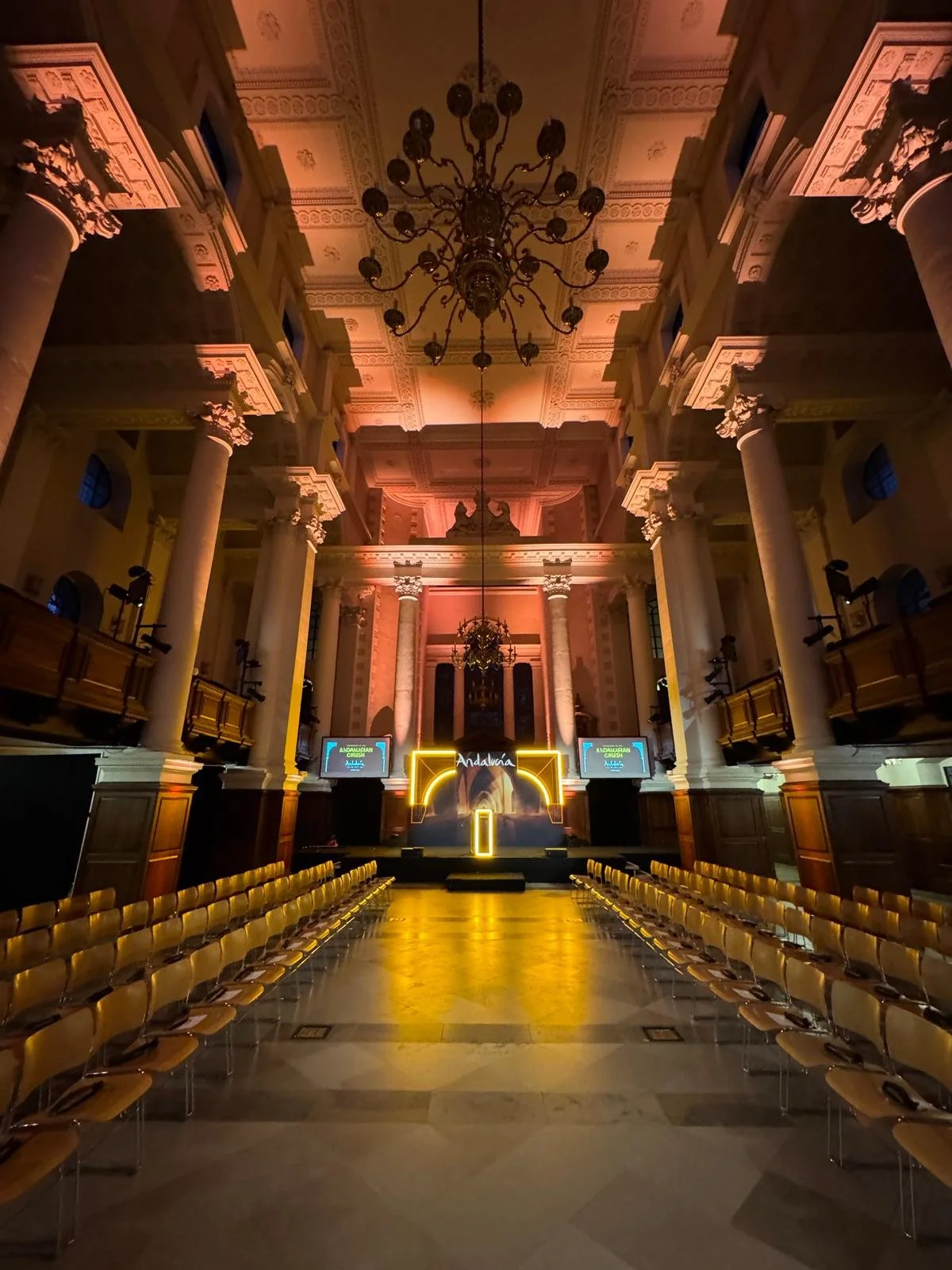 Central runway with rows of seating beneath warm event lighting in the Nave.
