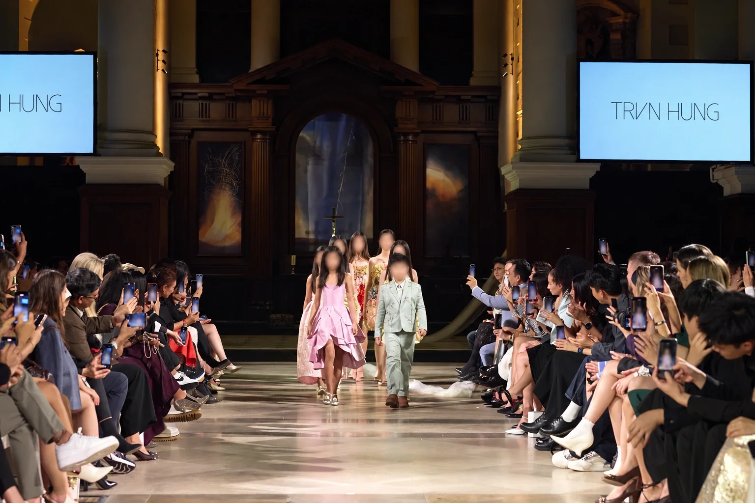 Models walking through the Nave between a seated audience at the TRAN HUNG fashion show.