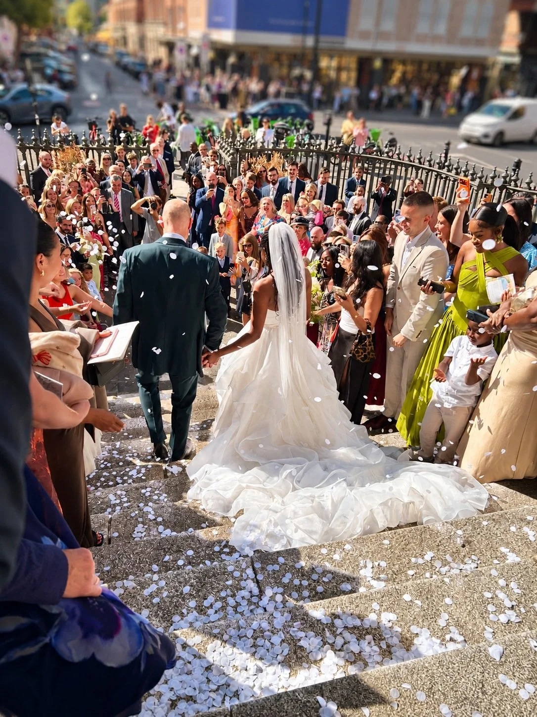 Couple surrounded by guests and confetti on the steps of Christ Church Spitalfields.