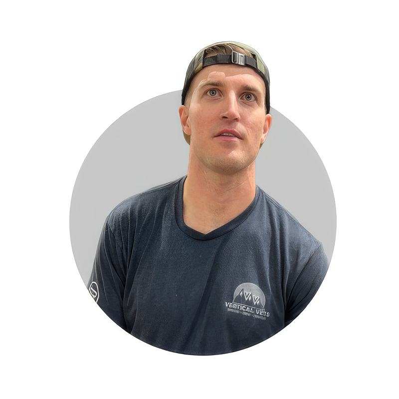 A man wearing a camouflage baseball cap and a black athletic shirt looking slightly upward.