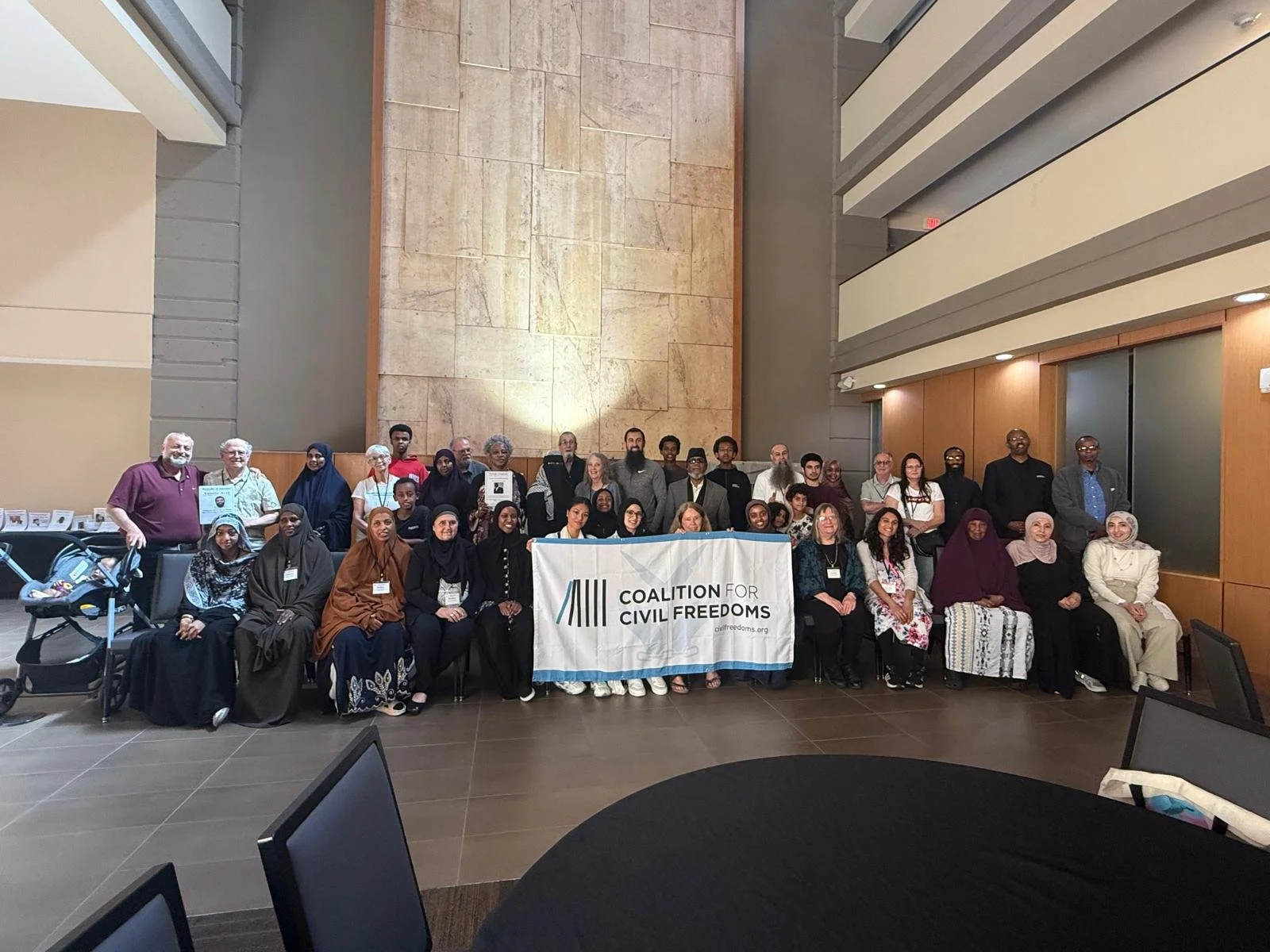 2025 CCF Conference. Large diverse group posing indoors behind a Coalition for Civil Freedoms banner.