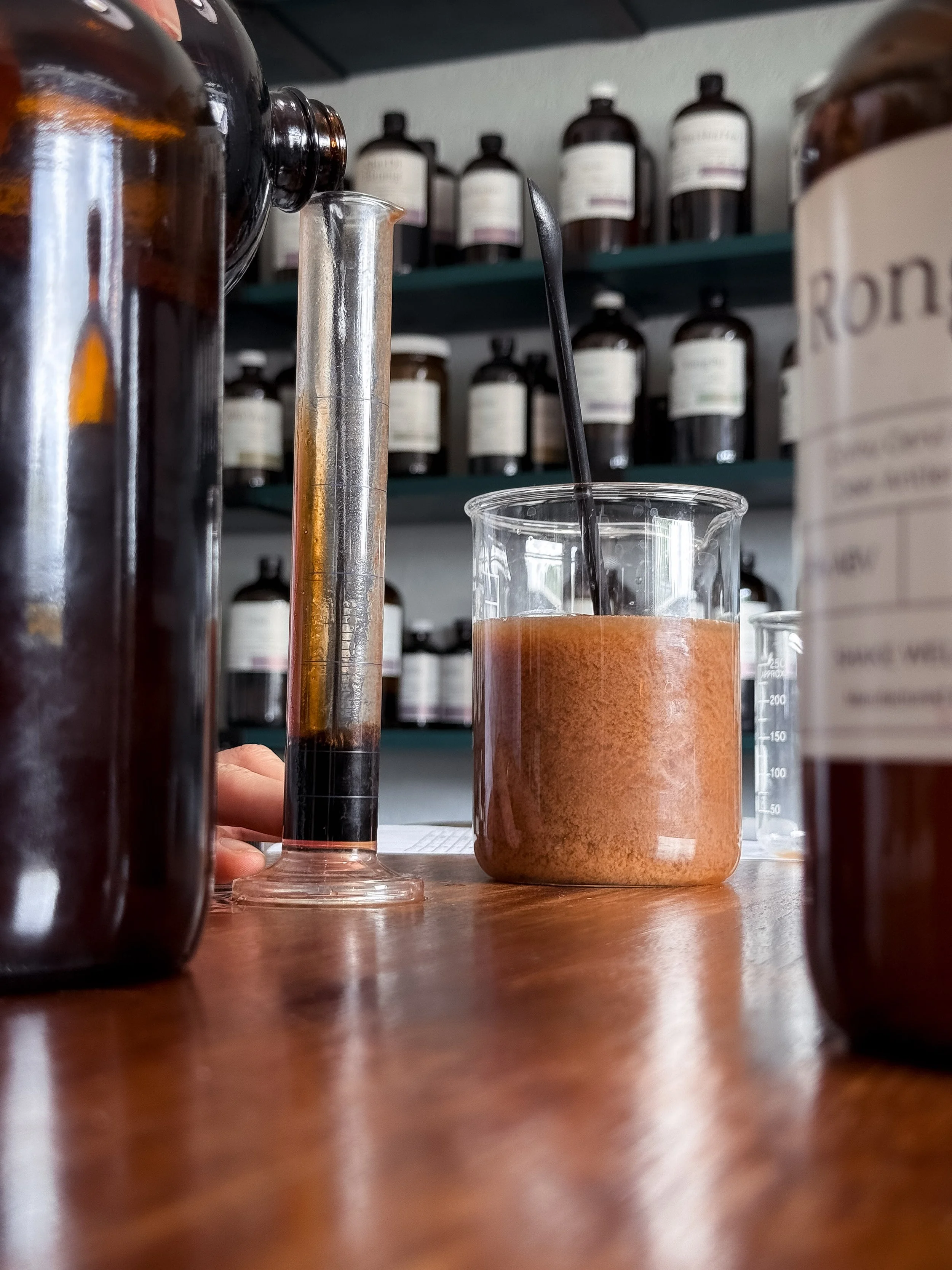 Laboratory workspace with glass beakers and test tubes filled with liquid herbal medicines.