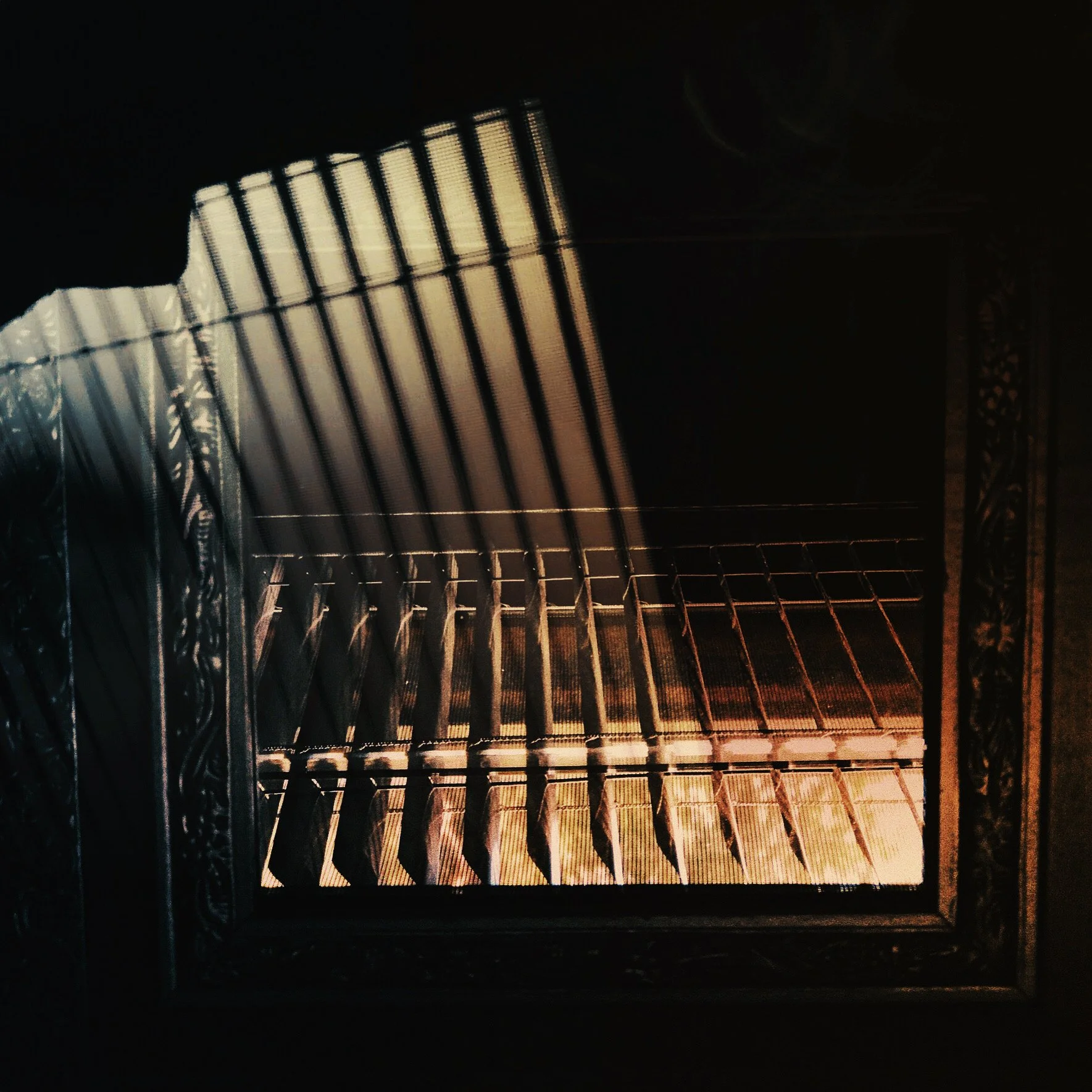 Inside an oven with the door open, showing empty oven racks illuminated by interior light.