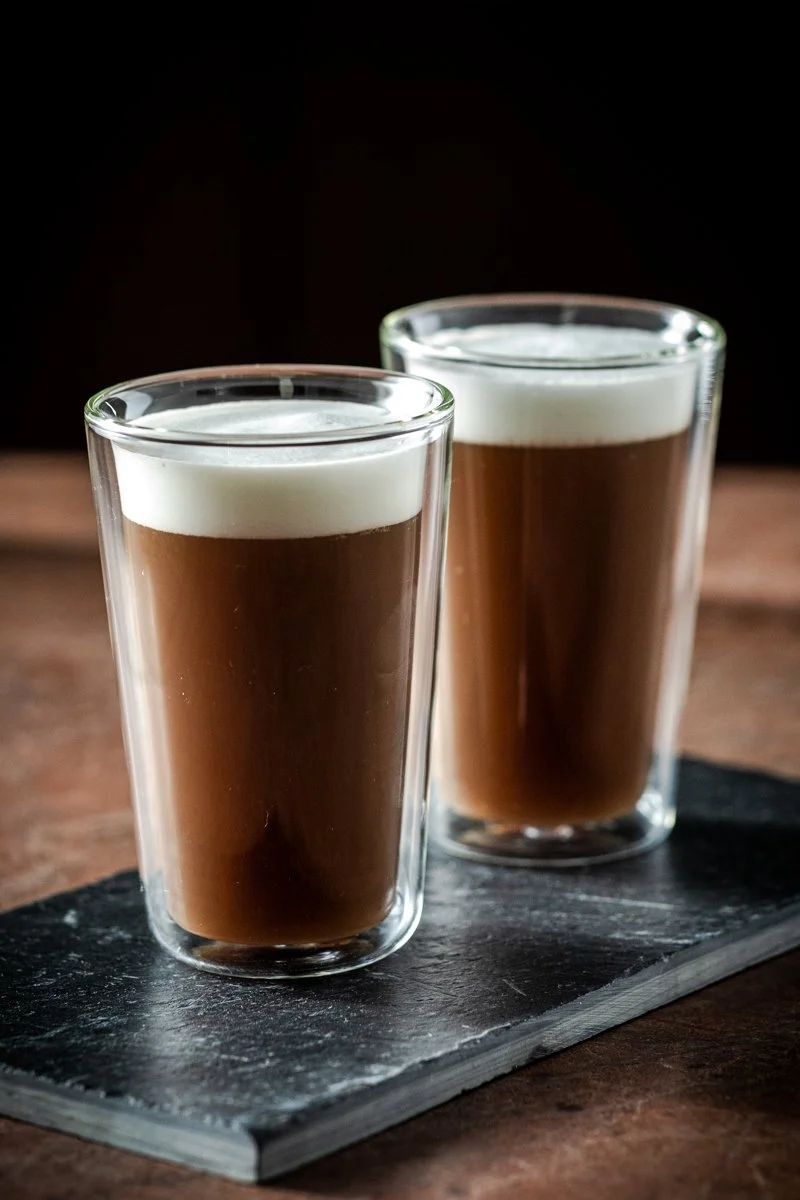 Due bicchieri di cioccolata calda con schiuma di latte su un piatto di pietra