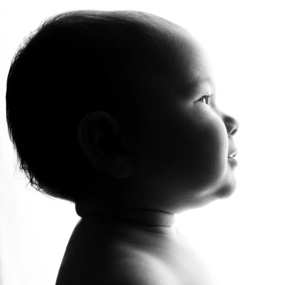 Ritratto di profilo di un bambino in bianco e nero, con illuminazione morbida.