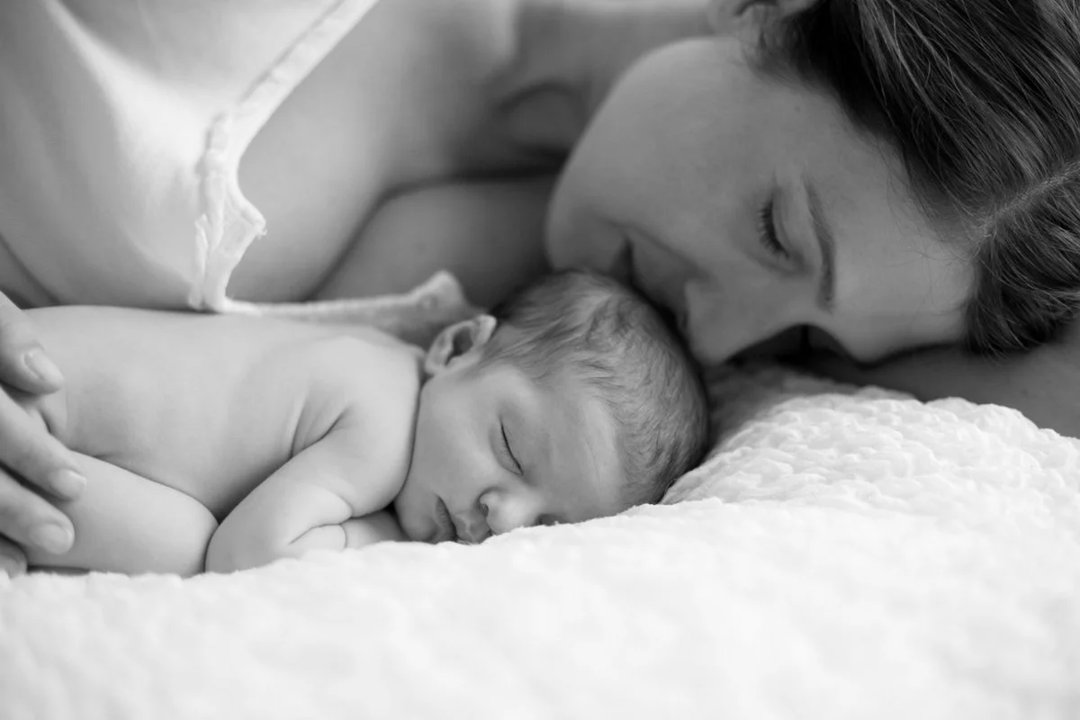ritratto fotografico di mamma stesa con neonato che dorme. Foto in bianco e nero.