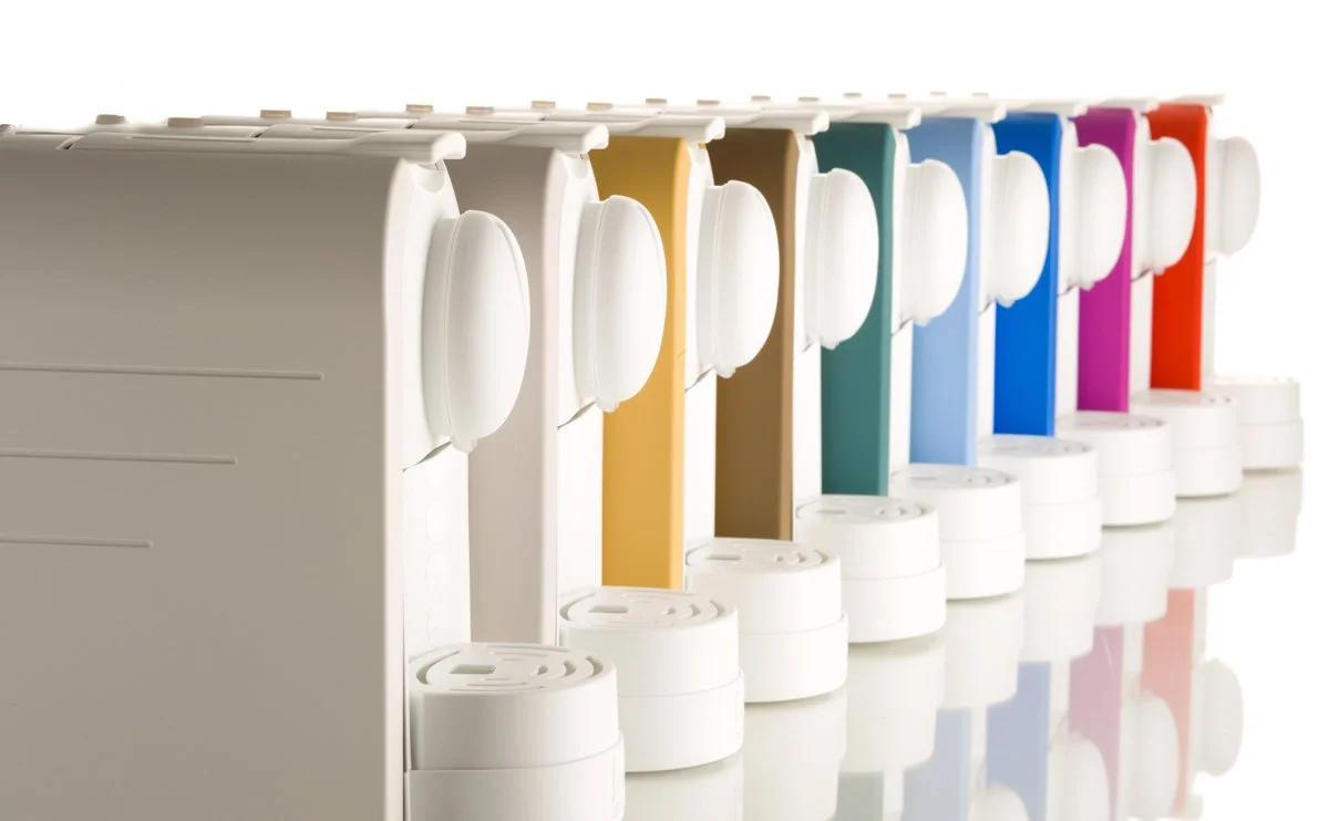 Macchine da caffè Nespresso con capsule di vari colori disposte in fila