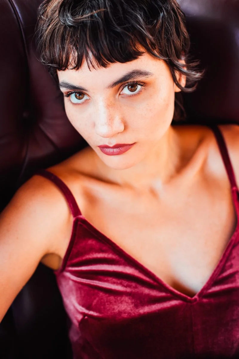 Ragazza con capelli scuri e corti, indossa un top di velluto rosso, vista dall'alto in un'immagine ravvicinata
