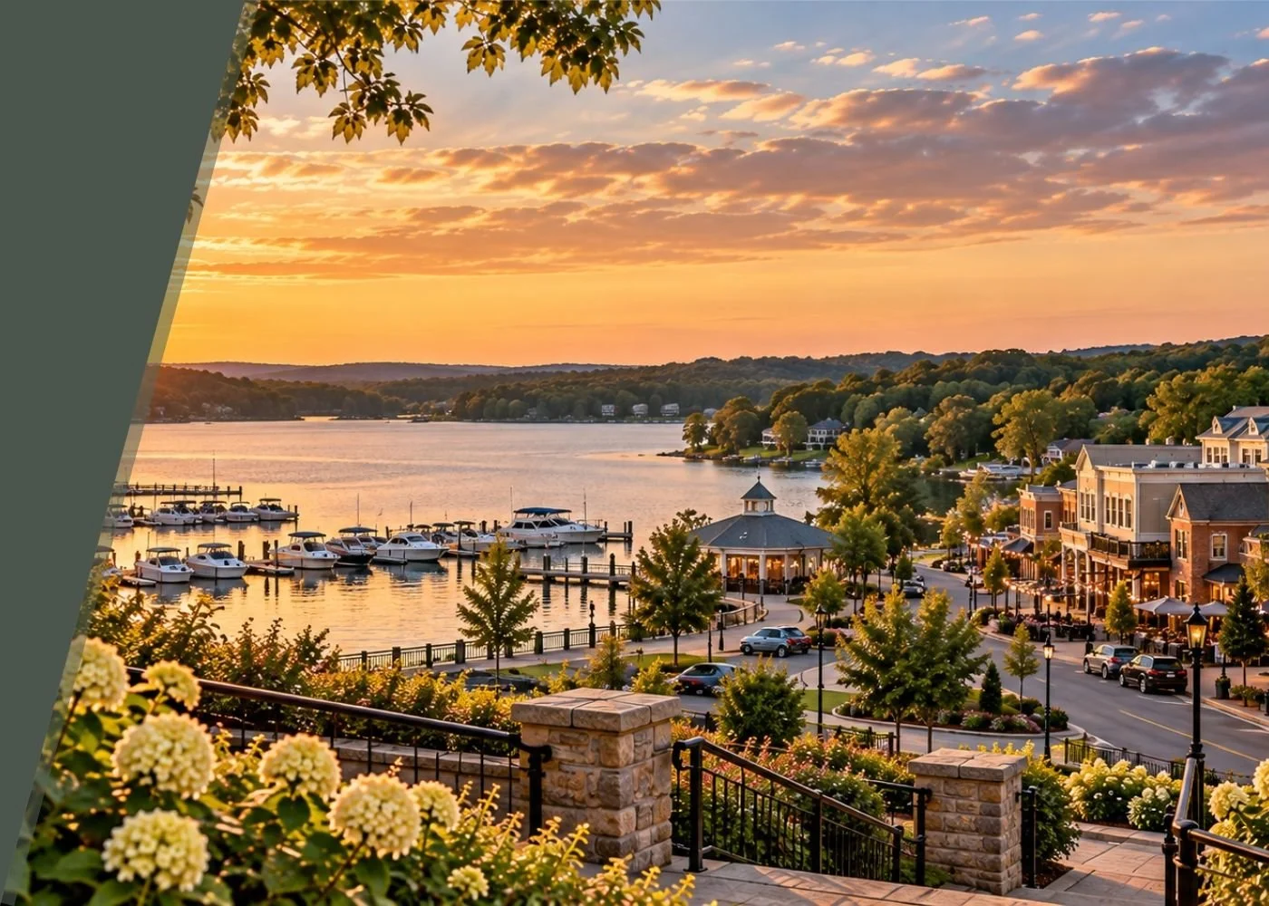 Sunset over a marina with boats, a pavilion, and a town with trees and buildings along the waterfront.