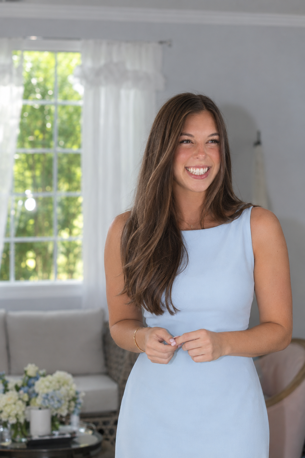 Smiling woman in a light blue dress standing in a bright living room