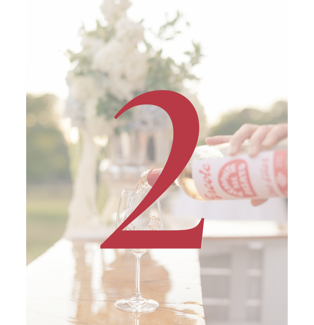 Person pouring sparkling rosé into a wine glass outdoors, overlaid with a large red number two