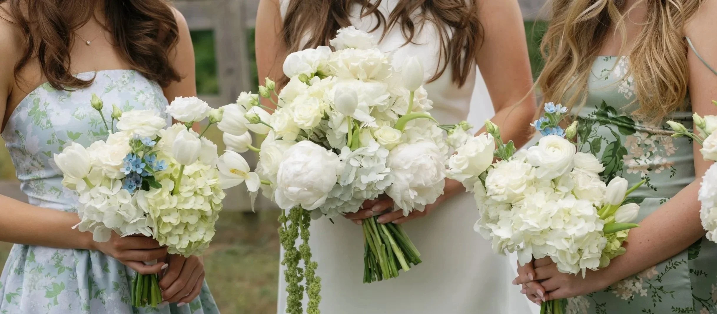 Bride and bridesmaids holding elegant white flower bouquets at a wedding