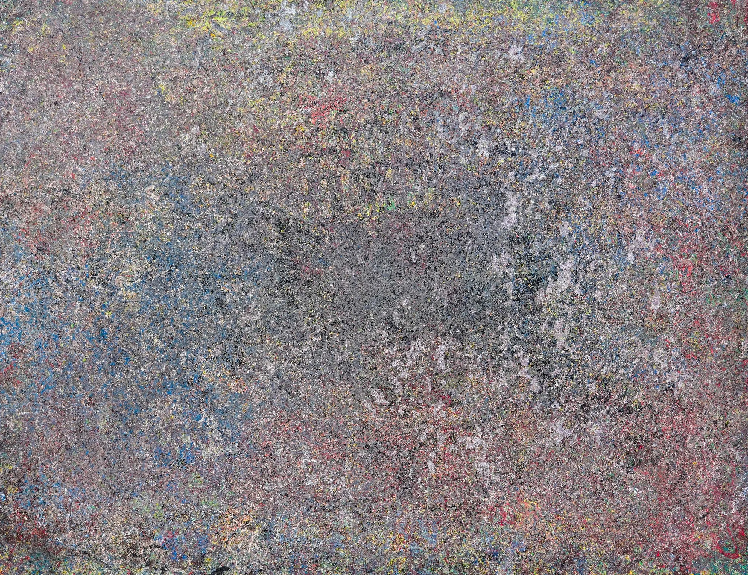 Abstract multicolored textured surface with dense speckled gray, red, blue, yellow, and green patterns