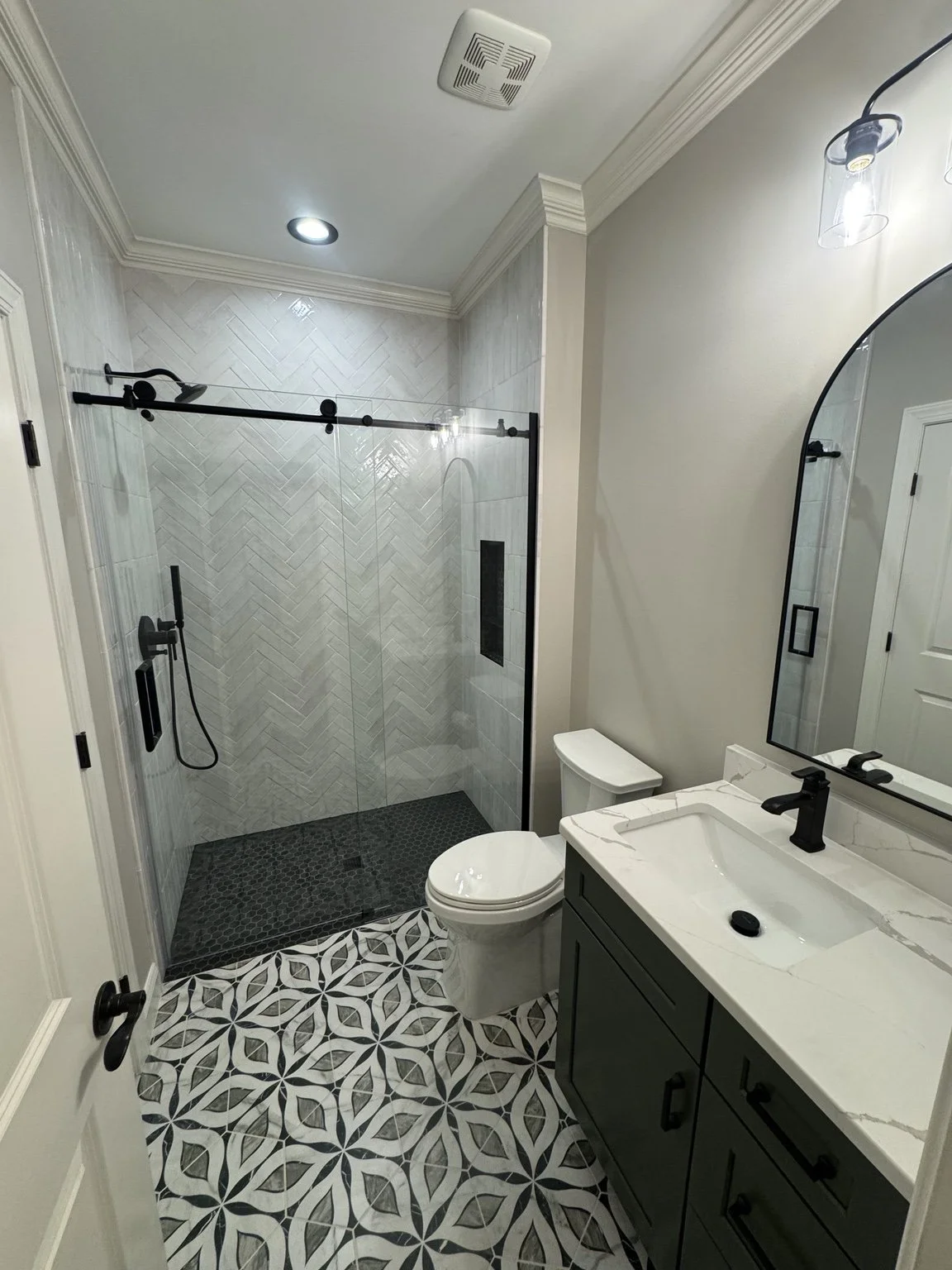 A smaller bathroom can still have plenty of character. Patterned floors and herringbone shower tile give this one a look of its own.