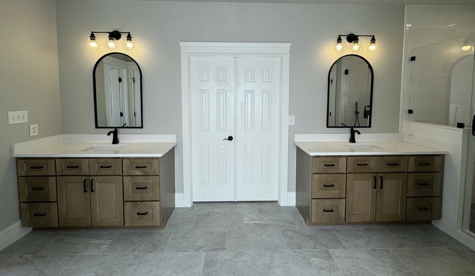 Warm wood vanities and arched mirrors give each person their own space while keeping the room feeling connected.