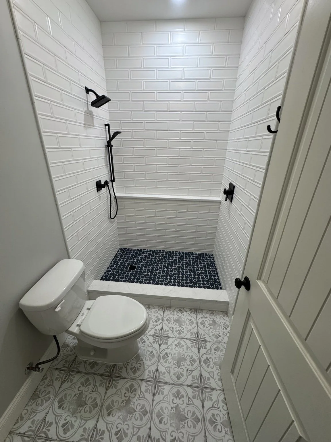 White subway tile and a patterned shower floor bring fresh life to a compact bathroom.