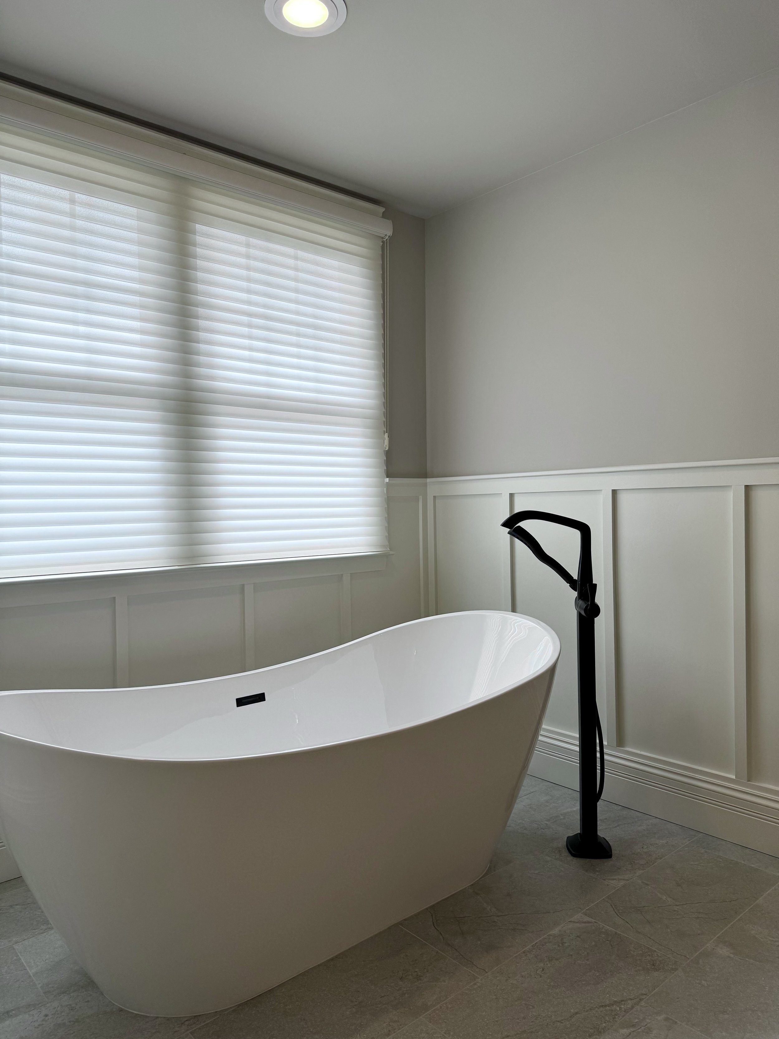 A freestanding tub beneath the window offers a quiet spot to slow down and enjoy a long soak.