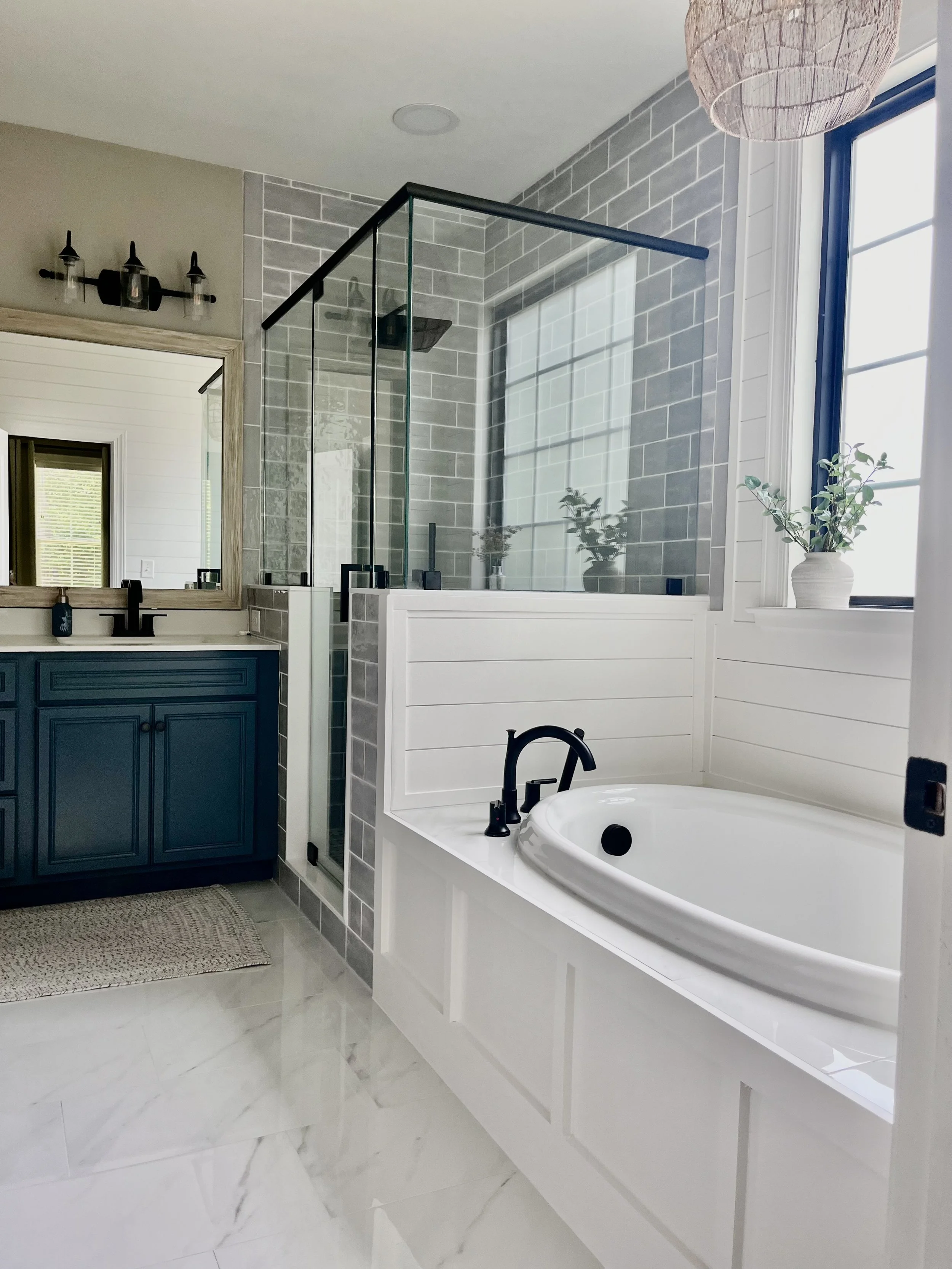 A rich blue vanity adds a little personality, while the glass shower and tiled tub surround keep the room light and open.